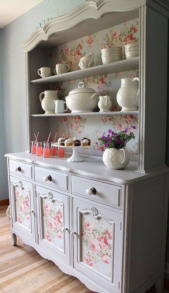 a china abinet with vintage floral wallpaper inside and on the compartments