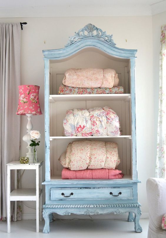 a pastel blue cupboard with no doors for storing blankets and bedspreads