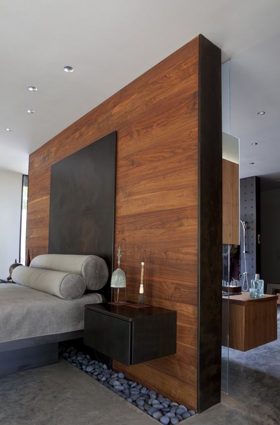 a tall headboard wooden wall acts as a space divider here and makes the bedroom private
