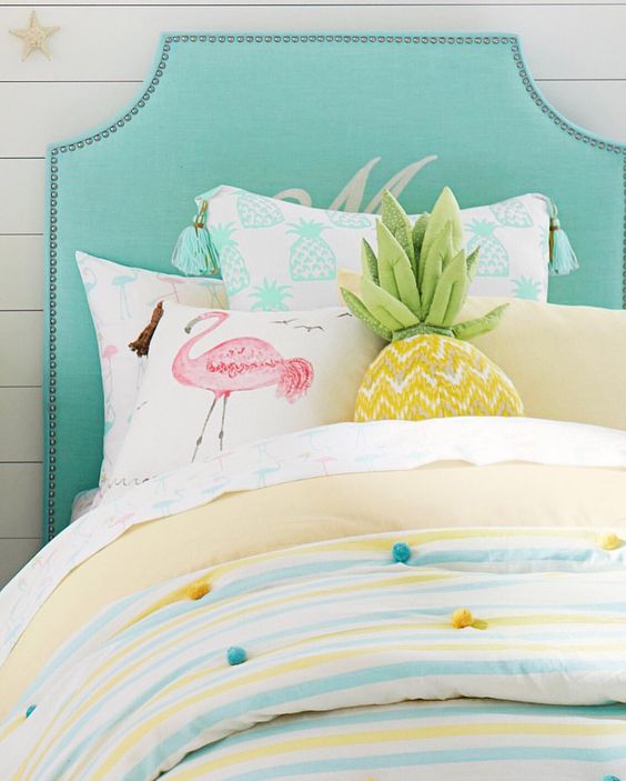 a pink flamingo pillow, a pineapple pillow and colorful pompom bedding