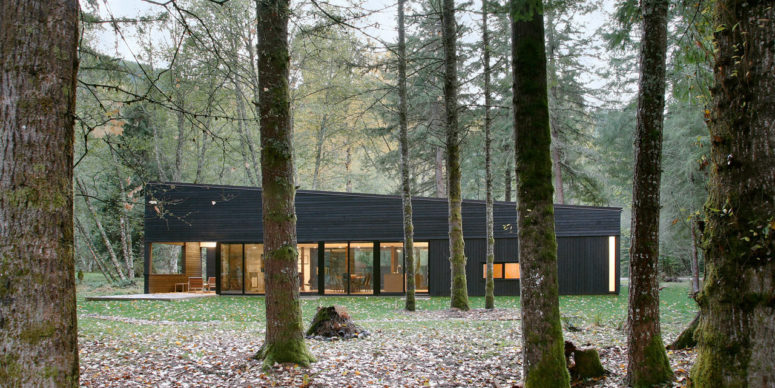 This gorgeous house with a black exterior is located in the forest, on a river and takes the advantage of the views