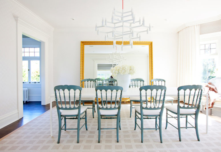 The dining room is spruced up with vintage blue chairs and an oversized gilded frame mirror to make it refined