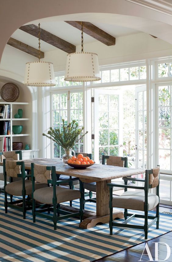 a coastal dining room with a rough wooden trestle dining table that adds texture and style