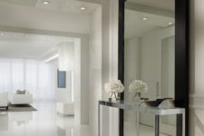 02 oversized wall mirror in a black frame defines the white entryway