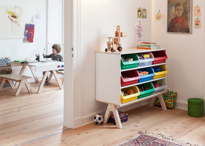 Creative and comfy in using shelving unit with plastic crates that can be removed and used throughout the room