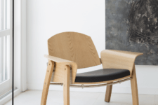 03 The Kimono chair is made of a leather cushion, light-colored wood and a metal detail that holds the back