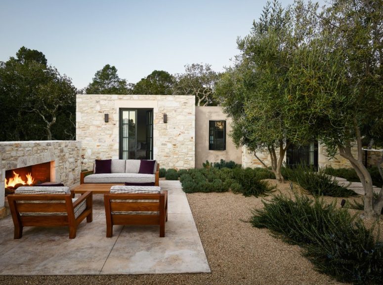 There are two volumes, which are connected with the outdoor space that features a stone fireplace and a sitting space