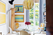 04 The dining room is accentuated with sunny yellow and blue, look how Pantone chairs fit the glass top dining table – this is a gorgeous idea