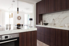 04 The kitchen features dark stained wooden cabinets and luxurious white marble countertops and a backsplash