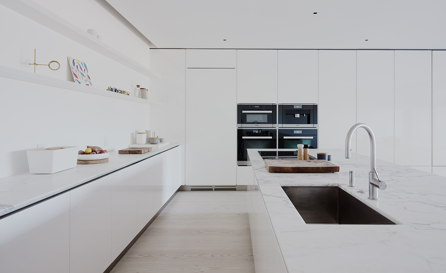 The kitchen is all-white, with no handle cabinets and built-in appliances to give it a sleek look