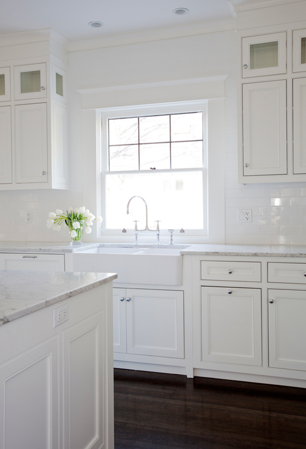 The kitchen is traditional and all-white, white marble countertops add a chic touch to the space