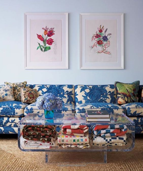 a blue floral print sofa contasts a modern Lucite coffee table
