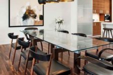 05 a chic modern table with stained wooden legs and a glass top, marching chairs with leather upholstery and black and gold pendant lamps