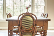 06 The dining zone is rustic and vintage, there are rattan chairs, a rustic wooden table and a glam crystal chandelier