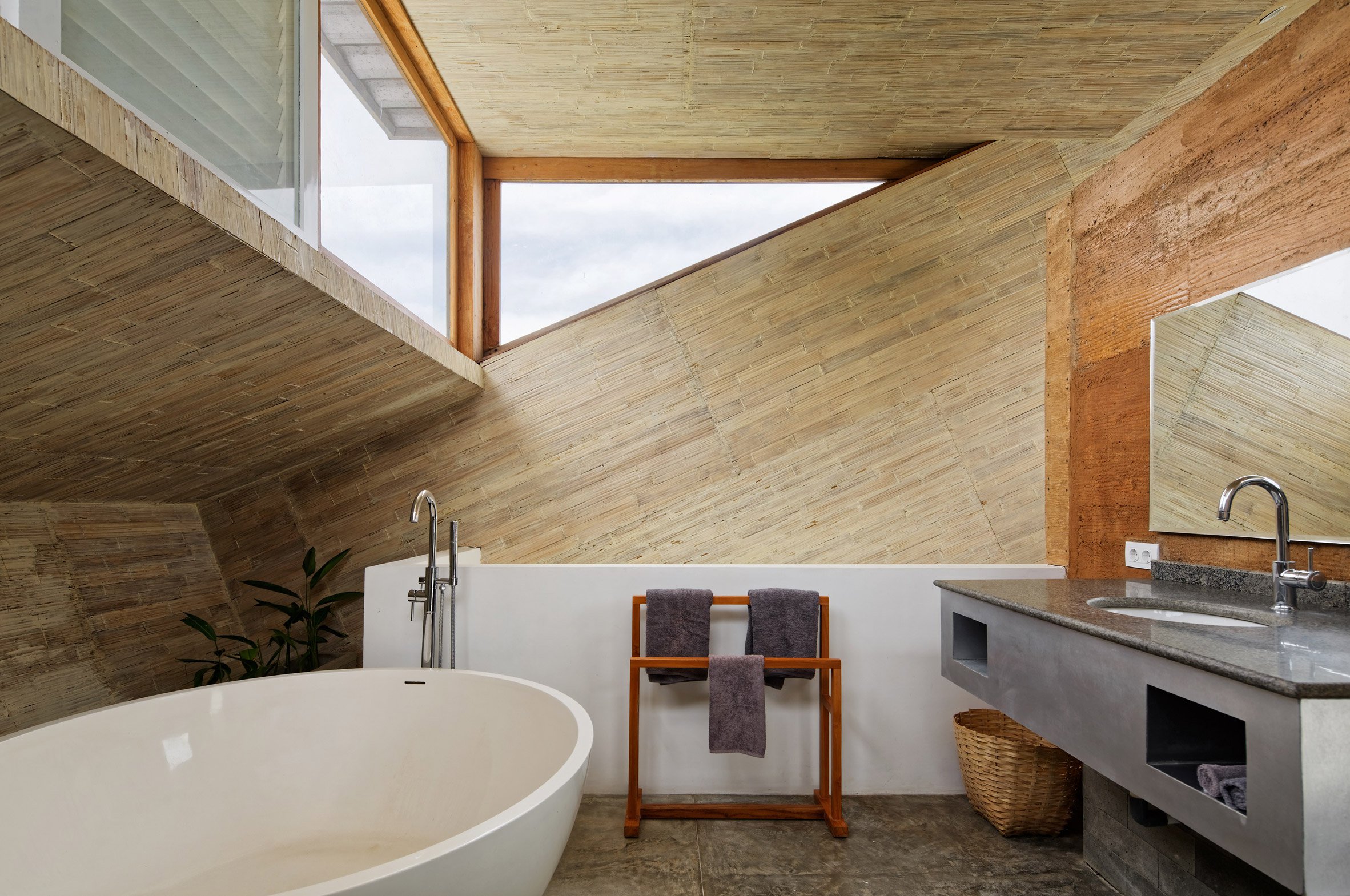 The en-suite bathroom features some windows, too, and there's a free-standing bathtub, a concrete vanity and much wood in the decor