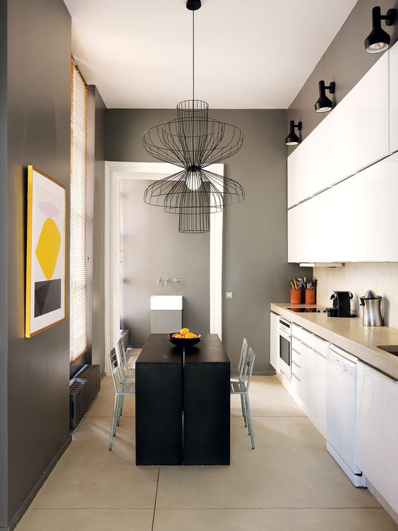 The kitchen is done in black, graphite grey and white, there's a matte back table and kitchen island in one and white cabinets, and of course a bold artwork to enliven it all