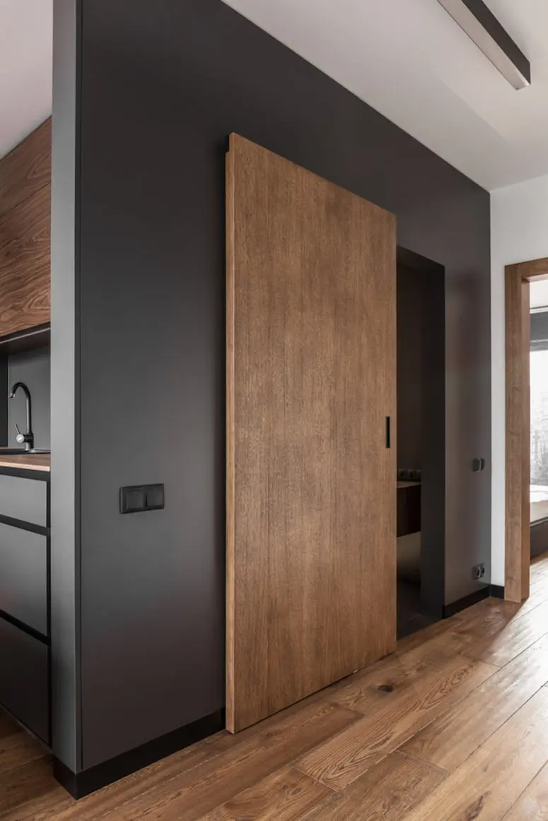The large wooden door matches the floor and ensures cohesiveness throughout the apartment