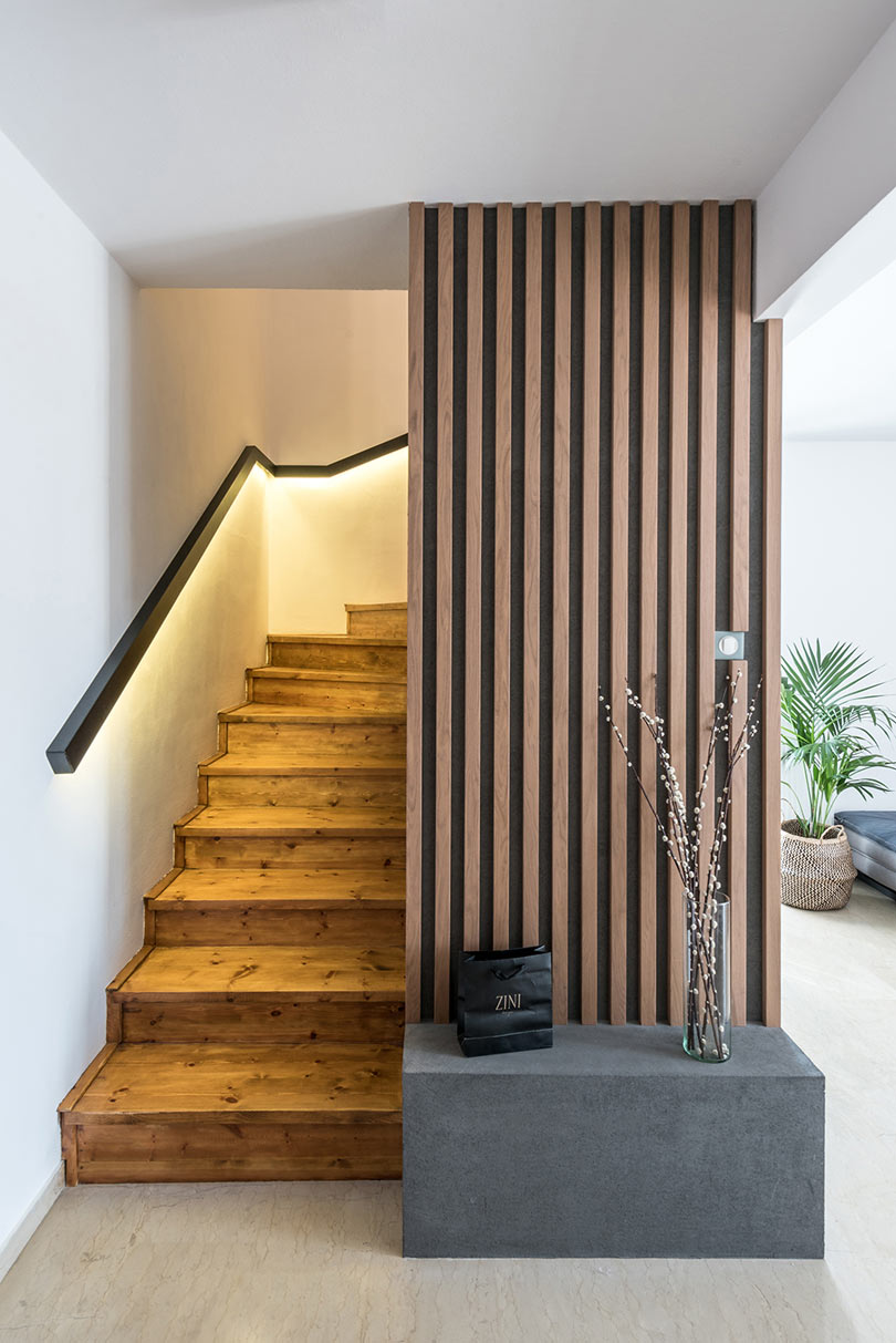 The staircase is wooden, with lit up railing and a concrete bench