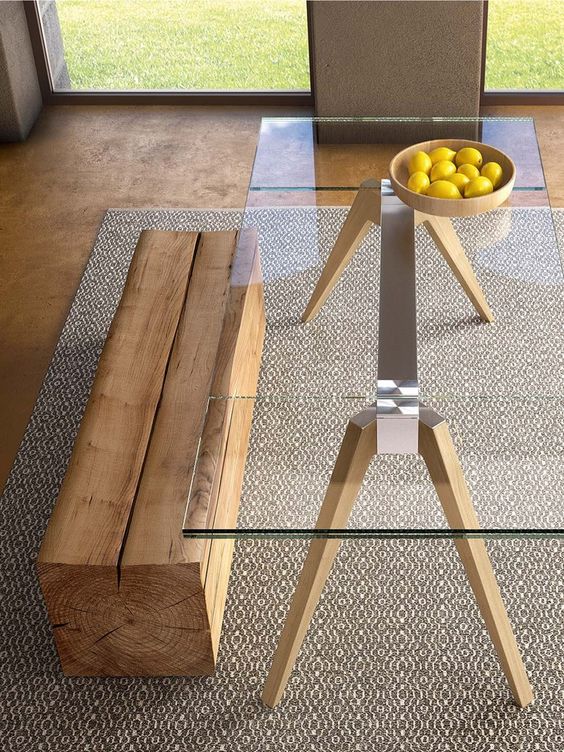 a table with a metal frame and wooden legs, a clear glass tabletop and a piece of wood as a bench for both a modern and rustic look