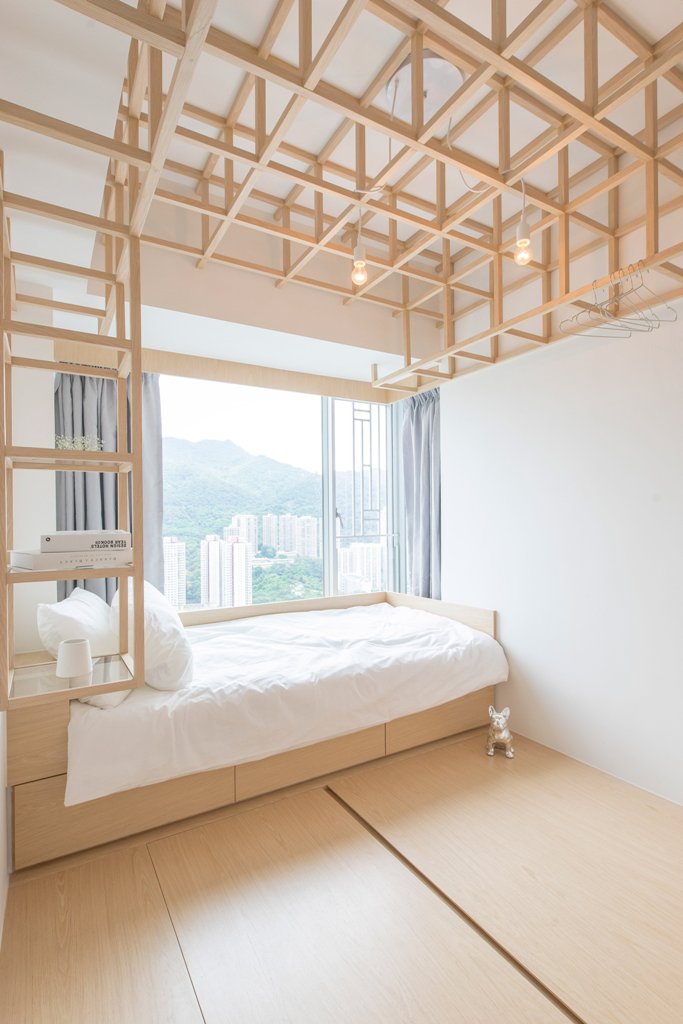 The guest bedrom features a bed and wooden frames over it that come into shelves in the headboard, looks super creative