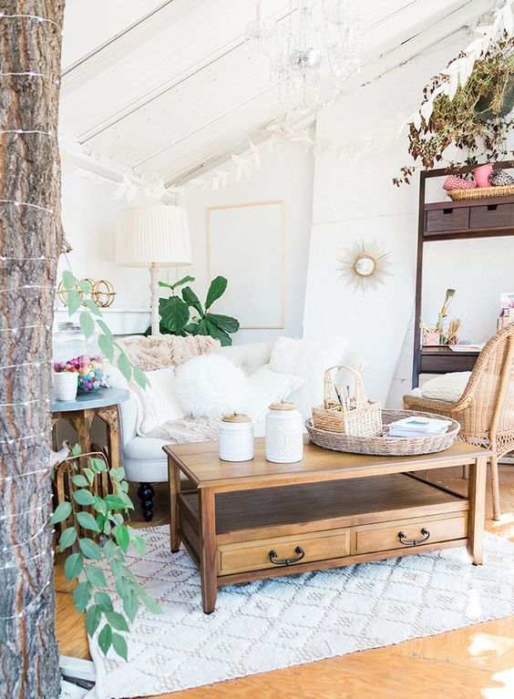 a boho living room in white with natural wood touches, a refined chandelier and potted plants
