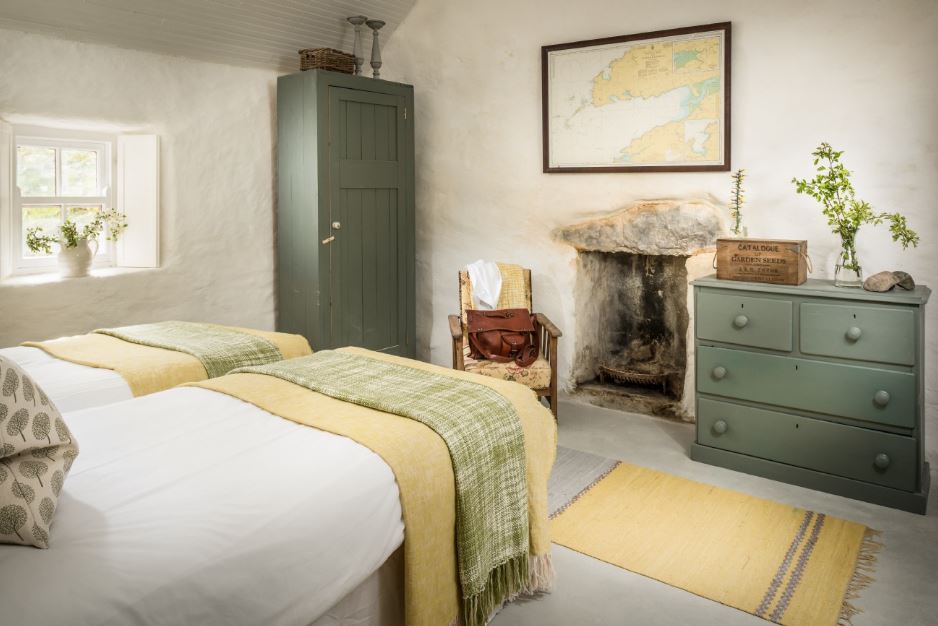 The guest bedroom is decorated in muted green and yellow, there's an antique hearth and a small window