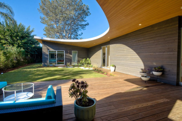 The house wall and the deck are clad with the same wood, which makes the space more inviting and cool