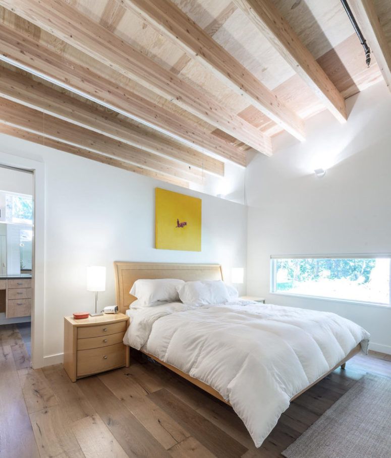 The master bedroom features wooden beams, floors, furniture and a narrow horizontal window to keep privacy, which makes it very cozy