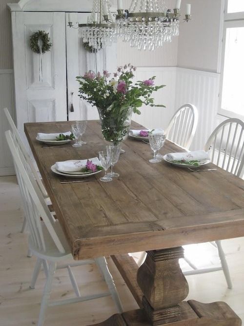 a whitewashed shabby chic dining room is enlivened with a large wooden trestle dining table