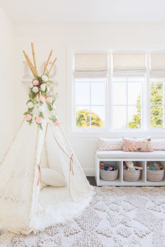 a play nook with a white lace teepee, a window bench with toy storage for a girl's playroom