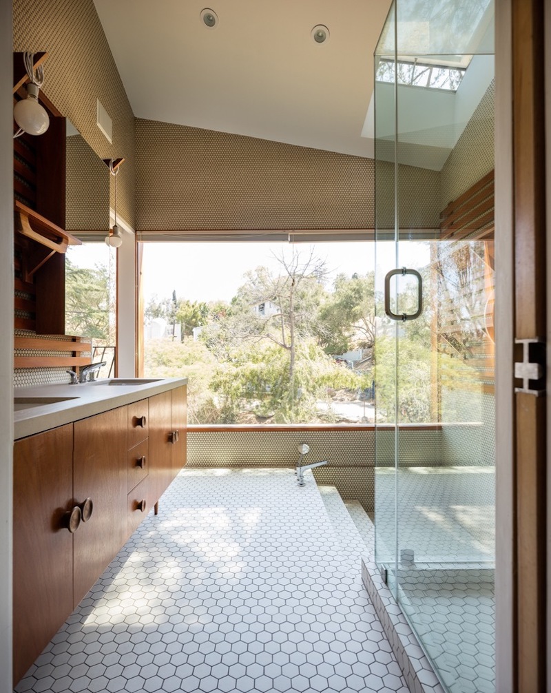 The bathroom is clad with hex tiles and there's a creative bath area with a view