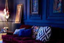 11 a moody cobalt blue space is made outstanding with a plum-colored velvet sofa