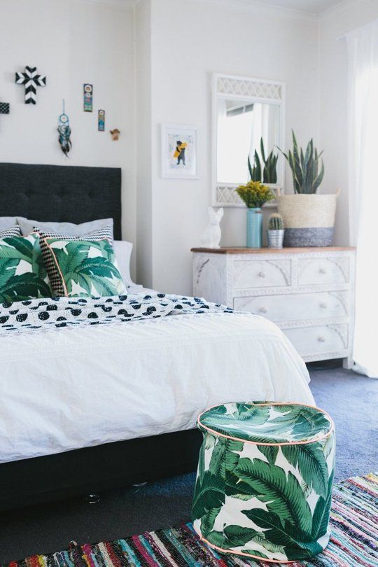 tropical leaf print pillows and a matching ottoman for a summer bedroom
