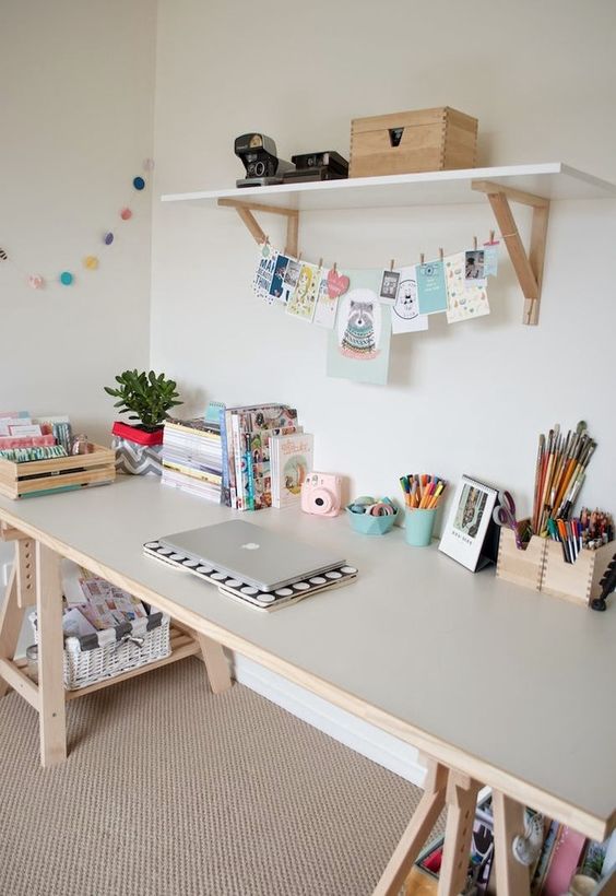 A kid's study space with a light colored trestle desk, which has storage compartments
