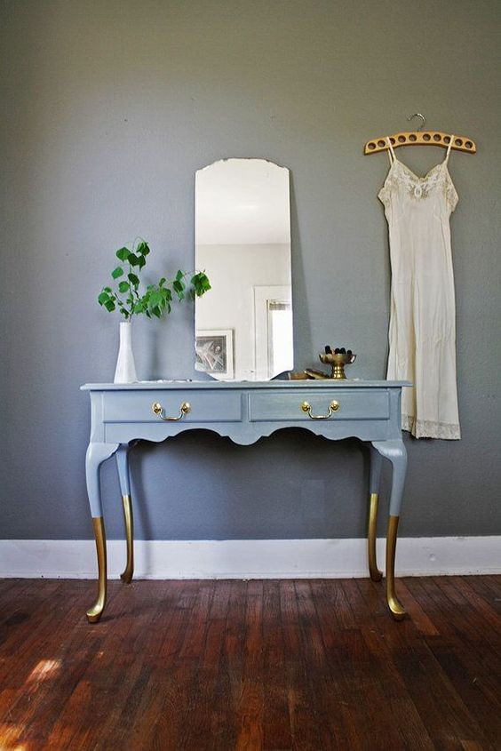 a vintage desk painted blue, with gilded legs and brass handles to use as a vanity