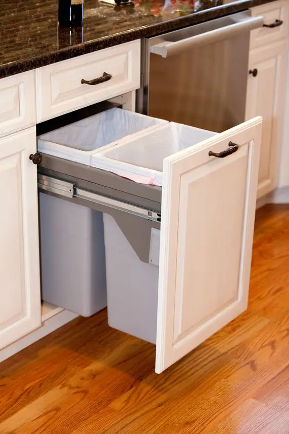 one of the kitchen cabinets holds pull out trash cans