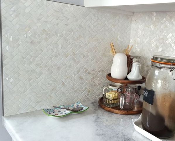 Mother of pearl tiles clad in a herringbone pattern for sprucing up a neutral kitchen