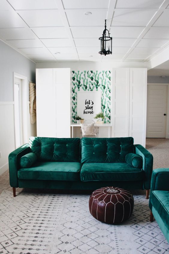 two emerald velvet sofas echo a cactus print wall