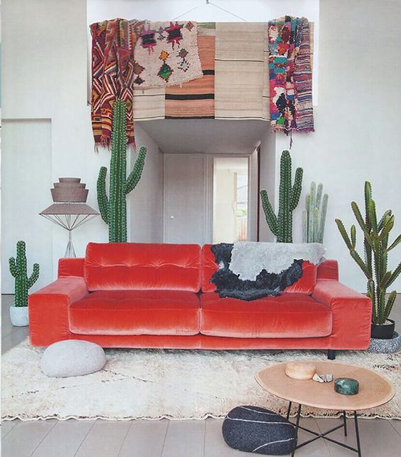 Desert inspired space with a fiery red velvet sofa and cacti