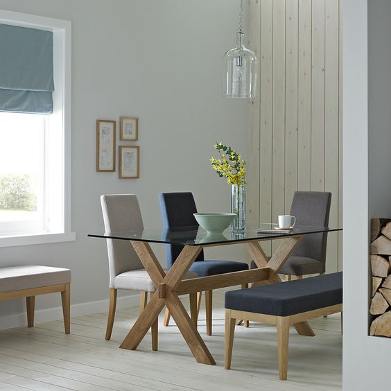 a trestle table with a glass tabletop and comfy upholstered chairs for a cozy and simple dining space