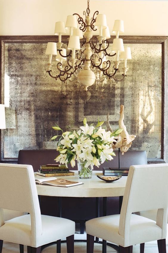a dining room made more refined and adorable with an oversized faded mirror in a vintage frame