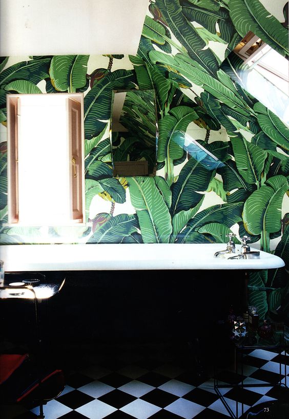 retro-inspired bathroom with palm leaf print wallpaper and a black bathtub