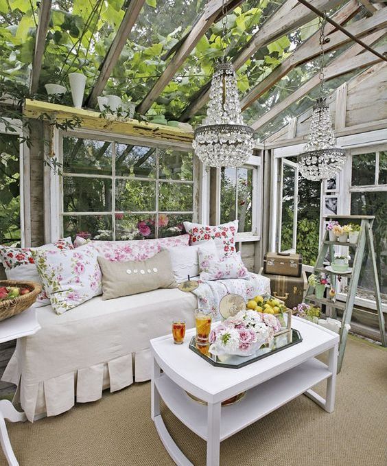 vintage-inspired glam she shed, a daybed with floral print pillows and glam chandeliers