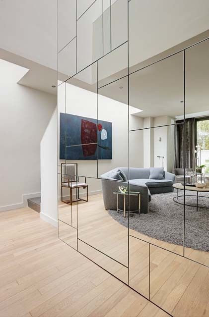 a geometric mirror wall visually doubles the living room and it looks much bigger