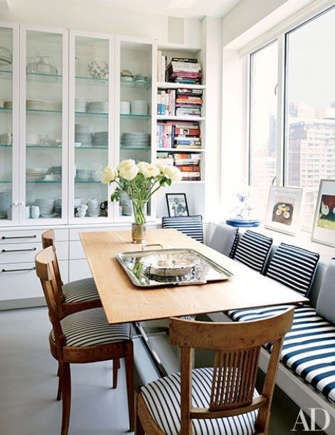 striped upholstery of the bench and chairs adds style to this dining space by the window