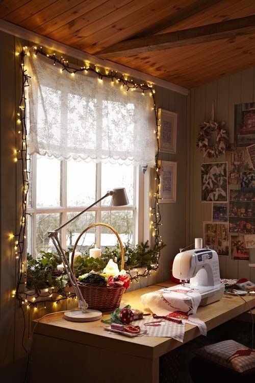 a cozy sewing room with string lights, a table and an inspiration wall with photos