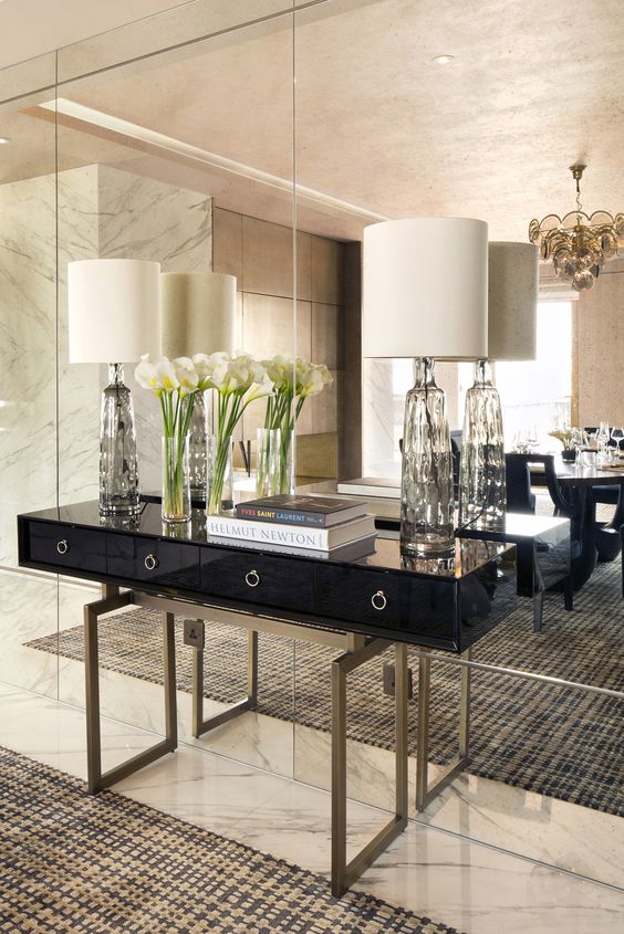 a mirror wall adds luxury to this living room together with marble and brass details