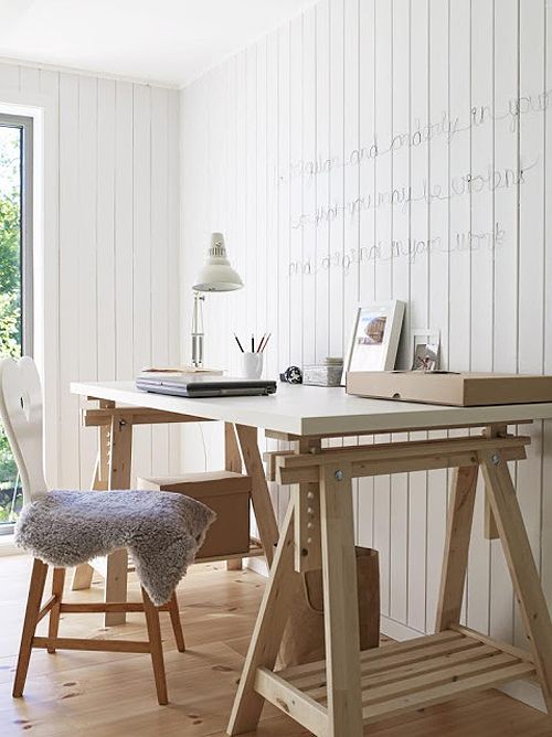 a white and light-colored wood trestle desk has additional open storage compartments