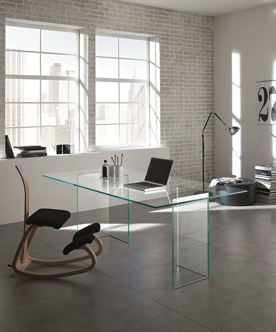 Minimalist and industrial home office with a clear glass desk and an eye catching upholstered chair