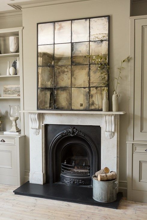 a vintage space with a fireplace is highlighted with a faded mirror over the mantel